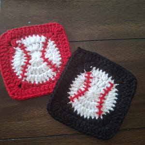May include: Two handmade crochet baseball coasters. One is red with a white baseball design and red stitching. The other is black with a white baseball design and red stitching. Both are square.