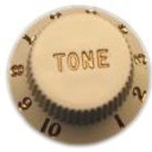 Pode incluir: Três botões de guitarra dourados com marcas pretas. Os botões são etiquetados como "VOLUME" e "TONE".