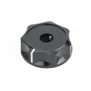 Pode incluir: Botão preto de plástico com uma linha branca e um furo redondo no centro.