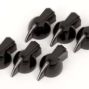 Peut inclure: Six boutons de guitare noirs avec une bande blanche. Les boutons ont un design pointu art déco.