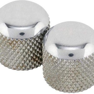 Könnte beinhalten: Zwei silberne Gitarrenknöpfe mit einem Diamantenmuster. Die Knöpfe sind rund und haben eine glatte, glänzende Oberfläche.