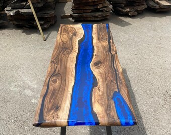Puede incluir: Mesa de madera artesanal con diseño de río de resina azul. La mesa presenta vetas de madera marrón oscuro y una base de metal negro. La mesa mide aproximadamente 152 cm de largo y 76 cm de ancho.
