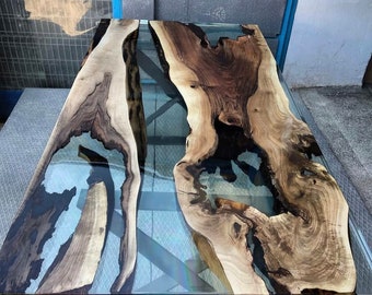 Puede incluir: Mesa de madera artesanal con un centro de resina epoxi transparente. La mesa presenta patrones de vetas de madera natural en tonos marrón, beige y crema. La mesa mide aproximadamente 183 cm de largo y 91 cm de ancho.