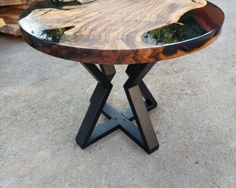 May include: A round wooden table with a dark, glossy finish and a unique wood grain pattern. The tabletop is supported by a black metal base with an X-shaped design. The table is approximately 36 inches in diameter.