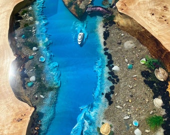May include: A handcrafted wooden table with a river design. The river is made of blue resin with a boat, bridge, and beach details. The table's edges are natural wood, and the river features a turtle and seashells.