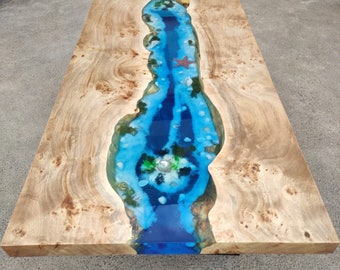 May include: A rectangular wooden table with a river-like design. The river is made of blue resin with a starfish and other decorative elements. The wood has a light brown color with unique patterns.