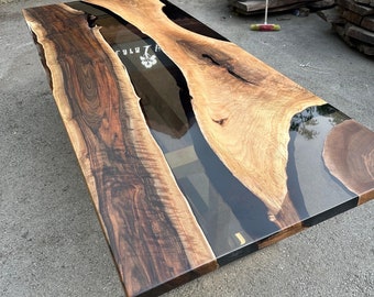 Könnte beinhalten: Ein großer, rechteckiger Holztisch mit dunklem, glänzendem Finish. Die Tischplatte weist ein natürliches Holzmaserungsmuster mit einem klaren, glänzenden Epoxidharzfluss in der Mitte auf. Der Tisch ist etwa 254 cm lang.