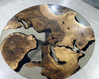 Könnte beinhalten: Runder Couchtisch aus Holz mit einzigartigem Design. Der Tisch hat ein hellbraunes Holzmaserungsmuster mit dunkelbraunen und transparenten Harzakzenten. Der Tisch hat einen Durchmesser von ca. 100 cm.