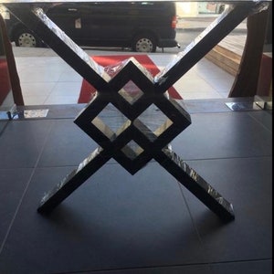 Pode incluir: Base de mesa de metal preto com um design geom&eacute;trico. A base apresenta um padr&atilde;o central em forma de diamante com pernas angulares que se cruzam. A base da mesa &eacute; envolvida em pl&aacute;stico protetor.
