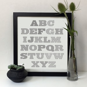 Puede incluir: Impresión de alfabeto en blanco y negro con un patrón geométrico en un marco negro. Las letras están en negrita y están dispuestas en orden alfabético.