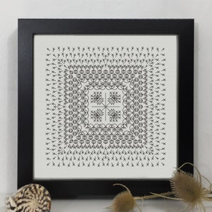 May include: Black and white embroidery design in a square frame. The design features a geometric pattern with a central cross shape.