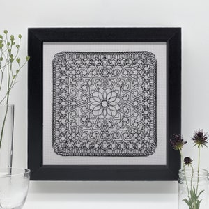 May include: Black and white geometric pattern framed in a black frame. The pattern is a repeating design of stars and squares.