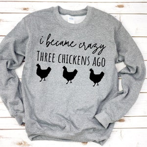 May include: Gray sweatshirt with the text "I became crazy three chickens ago" and three black chicken silhouettes.