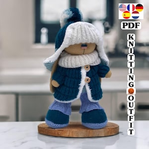 Peut inclure: Un lapin en crochet portant un manteau bleu, une écharpe blanche et un chapeau bleu avec un pompon blanc. Le lapin est debout sur une base en bois. PDF Knitting Outfit.
