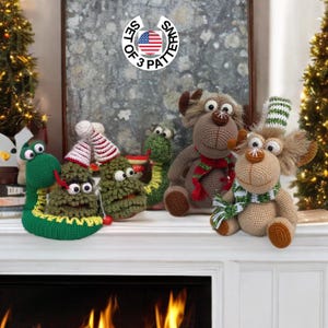May include: Set of three crochet Christmas ornaments. A green snake, a green Christmas tree, and a brown reindeer with a red and white scarf. The ornaments are sitting on a white fireplace mantel.