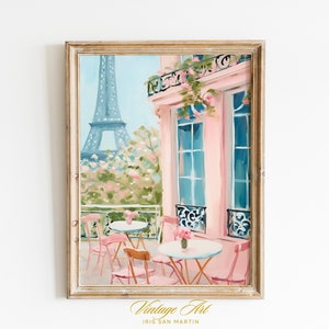 May include: A painting of a Parisian cafe with pink walls and a view of the Eiffel Tower. The cafe has tables and chairs on the patio, with pink flowers and greenery. The painting is framed in a light wood frame.
