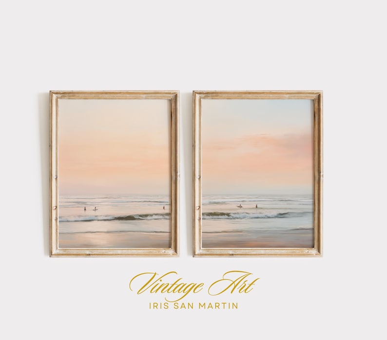May include: Two framed beach art prints. Each print depicts a serene ocean scene with surfers, under a pastel sunset sky. The frames are a light wood color, adding a vintage aesthetic to the artwork.