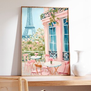 May include: A painting of a Parisian cafe with pink tables and chairs on a balcony overlooking the Eiffel Tower. The building is painted in a soft pink with blue windows and a balcony with pink flowers.