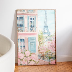 Pu&ograve; includere: Un dipinto incorniciato di un edificio rosa con persiane blu e un balcone che si affaccia su una scena di strada a Parigi, Francia. La Torre Eiffel &egrave; visibile sullo sfondo, e ci sono fiori rosa in primo piano.