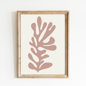 May include: Framed abstract art print featuring a coral-colored botanical design on an off-white background. The artwork is enclosed in a rustic, light brown wooden frame, creating a minimalist aesthetic. Ideal for home decor.