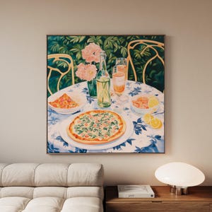 Puede incluir: Pintura enmarcada que representa una mesa puesta para una comida. Una pizza, aperitivos y bebidas están dispuestos sobre un mantel con estampado azul y blanco. Flores rosas en un jarrón y dos sillas son visibles en el fondo. La pintura está sobre un fondo de follaje verde.