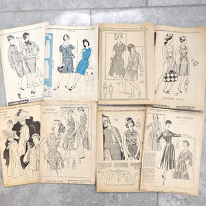 May include: A collection of vintage sewing pattern booklets featuring illustrations of women's fashion designs. The booklets display various dress styles, suits, and ensembles, with detailed sketches and text. The pages have a yellowed, aged appearance.