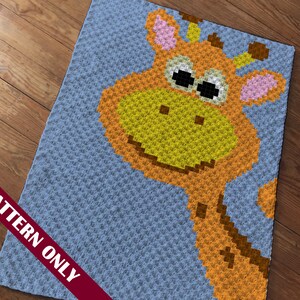 Puede incluir: Un patrón de crochet para una manta de bebé con una jirafa sonriente con manchas marrones. La jirafa está sobre un fondo azul claro.