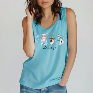 May include: A light blue tank top featuring a graphic of characters from the movie Frozen: Elsa, Sven, and Olaf. The text "Let it go" is written below the characters. The tank top has a scoop neck.