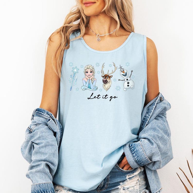 May include: Light blue tank top featuring Elsa, Kristoff, Sven, and Olaf from Frozen. The phrase "Let it go" is printed in black script below the characters. The tank top is sleeveless and made of a soft material.