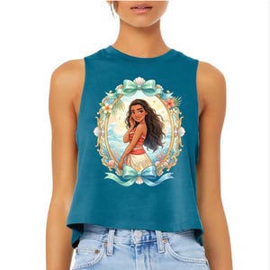 Puede incluir: Top corto sin mangas de color turquesa con una ilustraci&oacute;n enmarcada de una mujer de dibujos animados con pelo largo y oscuro, vestida con un atuendo rojo y blanco. El marco incluye conchas marinas, flores y lazos turquesa. El fondo es una escena de playa.