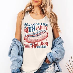 Peut inclure: Un débardeur blanc avec un motif de hot-dog et le texte "You look like the 4th of July makes me want a hot dog real bad" en rouge et bleu. Le débardeur est porté par une personne.