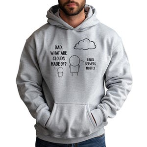 Peut inclure: Un sweat à capuche gris clair avec une poche avant et un cordon de serrage. Le sweat-shirt présente un graphique humoristique avec le texte "DAD. WHAT ARE CLOUDS MADE OF ?" et la réponse "LINUX SERVERS. MOSTLY."
