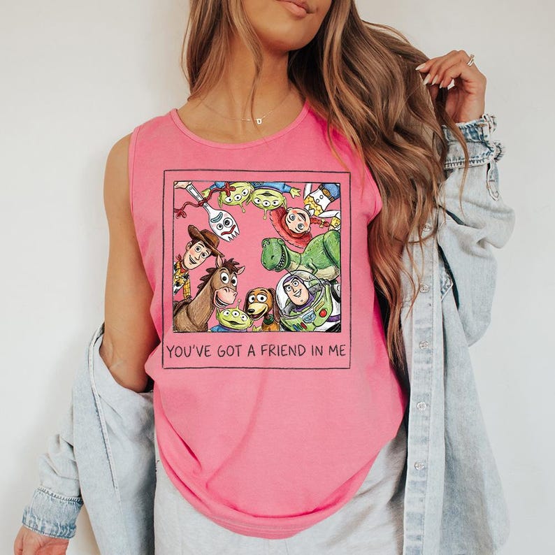 May include: Pink vest top with a framed graphic of Toy Story characters, including Woody, Buzz Lightyear, and the aliens. The text "YOU'VE GOT A FRIEND IN ME" is printed below the graphic. The top is sleeveless.