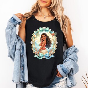 K&ouml;nnte beinhalten: Schwarzes Tanktop mit einer farbenfrohen Illustration einer Zeichentrickfigur in einem ovalen Rahmen. Der Rahmen enth&auml;lt Blumen, Muscheln und eine blaue Schleife. Die Figur tr&auml;gt ein rotes Oberteil und einen wei&szlig;en Rock.