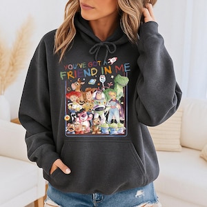 May include: Dark gray hoodie featuring a colorful graphic of characters from the movie Toy Story. The text "YOU'VE GOT A FRIEND IN ME" is above the graphic. The hoodie has a drawstring hood and a front pocket.