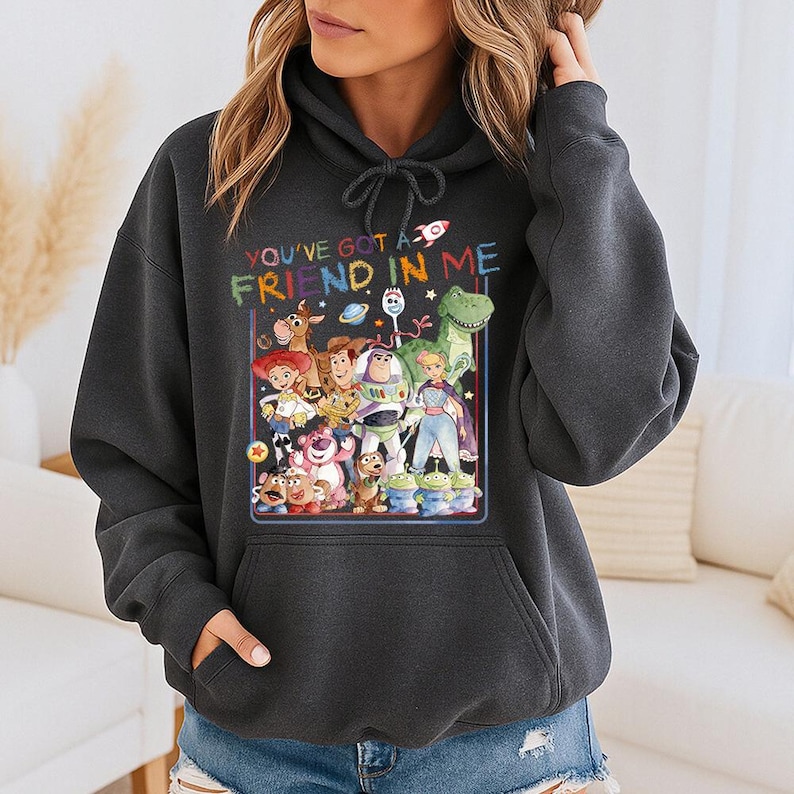 May include: Dark gray hoodie featuring a colorful graphic of characters from the movie Toy Story. The text "YOU'VE GOT A FRIEND IN ME" is above the graphic. The hoodie has a drawstring hood and a front pocket.