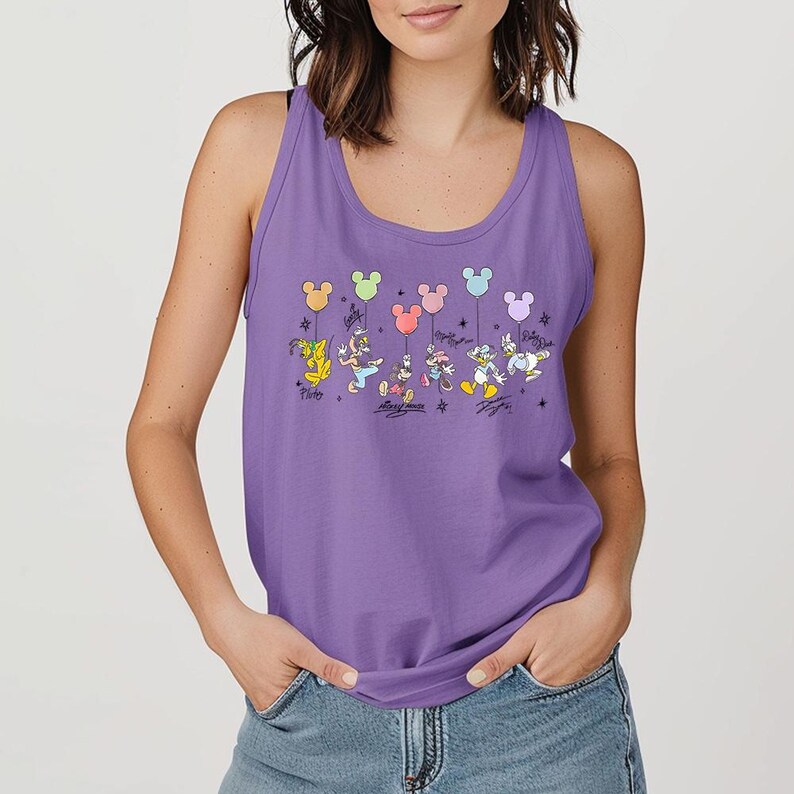 May include: A lilac tank top with a vibrant graphic of Disney characters, including Pluto, Mickey, Minnie, Donald, Daisy, and Goofy, holding Mickey Mouse-shaped balloons. Each character's signature is below. The top is sleeveless with a scoop neckline.