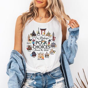Pode incluir: Camiseta branca sem mangas com a frase "I'm Making Poor Choices Around The World". O design apresenta ilustrações de marcos de vários países, incluindo a Torre Eiffel e o Coliseu.