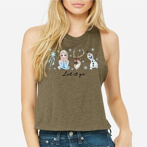 Pu&ograve; includere: Canotta verde oliva con una grafica di Elsa, Sven e Olaf di Frozen, fiocchi di neve e la scritta "Let it go". Il design &egrave; nei toni del blu, bianco e marrone.