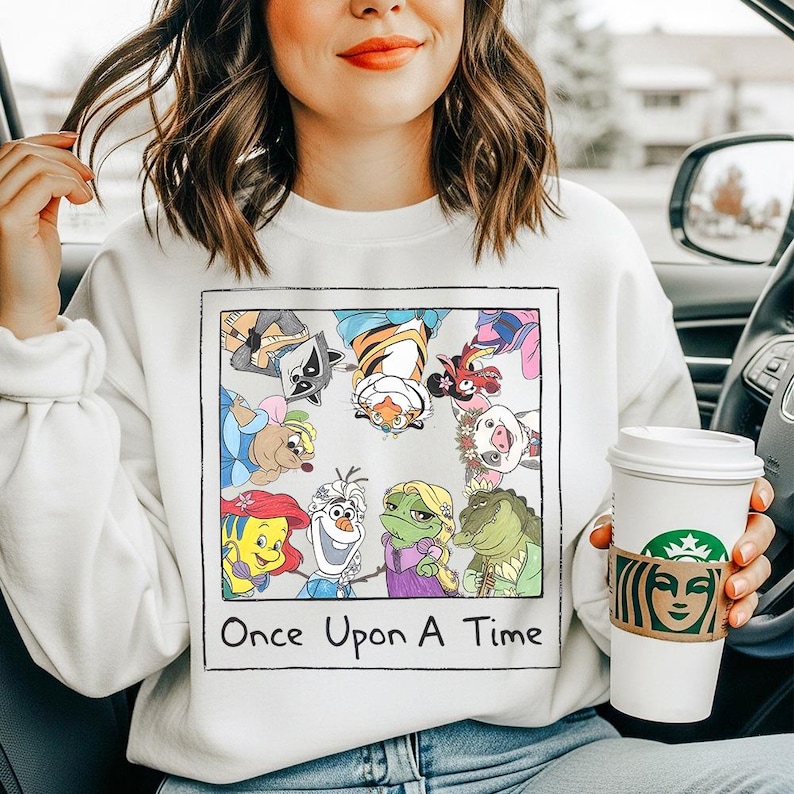 May include: White sweatshirt featuring a colorful graphic of cartoon characters. The graphic includes a variety of animated figures and the text "Once Upon A Time" in a black font. The sweatshirt is a casual style.