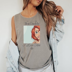 May include: Gray tank top featuring a graphic of a red-haired cartoon character with the text "But Daddy I Love Him". The tank top has a scoop neck and is made of a soft material. The graphic includes the year "1989".