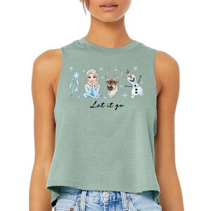 Pu&ograve; includere: Top corto verde salvia con una grafica dei personaggi del film Frozen, tra cui Elsa, Olaf, Sven e una bacchetta a fiocco di neve. La frase "Let it go" &egrave; scritta in corsivo nero. Il top &egrave; senza maniche.