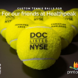 May include: A row of yellow tennis balls with black text. The text on the front ball reads "DOC LISTED NYSE".