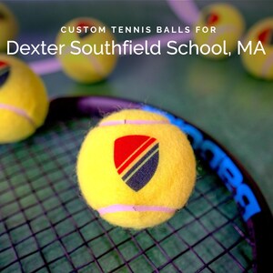 May include: Yellow tennis balls with a custom logo featuring a red, black, and blue shield design. The text "Dexter Southfield School, MA" is printed above the balls.