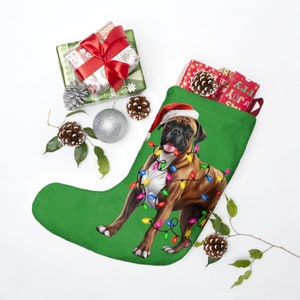 May include: A green Christmas stocking with a brown and white Boxer dog wearing a Santa hat and surrounded by colorful Christmas lights.