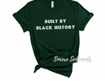 Puede incluir: Una camiseta verde oscuro con el texto "Built by Black History" en letras blancas.