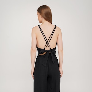 Peut inclure: Pantalon large noir avec un haut court noir assorti, doté d'un détail croisé dans le dos et d'un nœud papillon.
