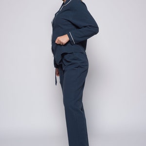 May include: A navy blue pajama set with a white trim. The top has a button-up front and long sleeves. The pants have a drawstring waist.