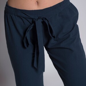 May include: Dark blue pants with a tie at the waist.
