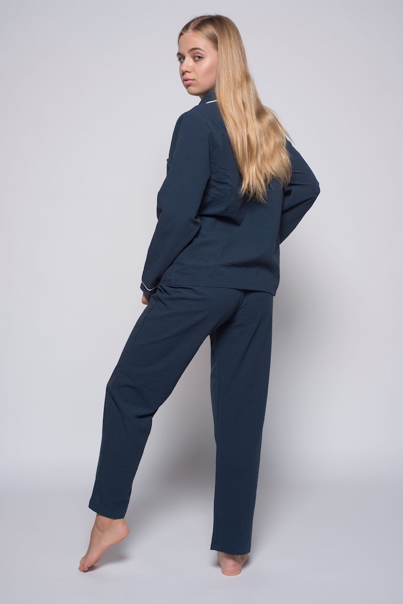May include: A dark blue pajama set with long sleeves and pants. The top has a white trim around the collar and cuffs.